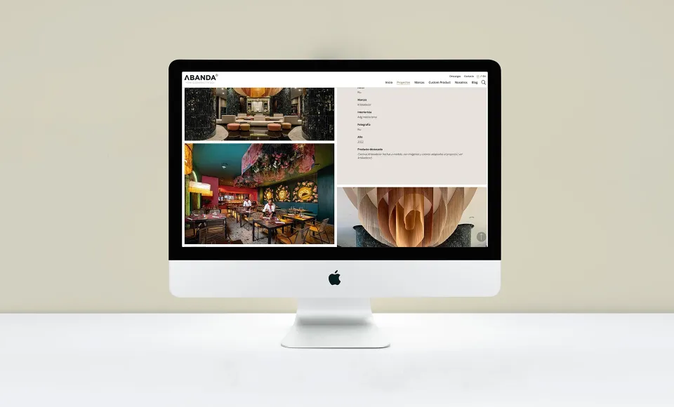 Web de Abanda en un iMac con la ficha de un proyecto y fotos de un local con interiorismo de color