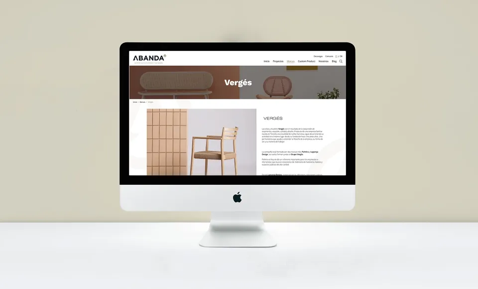 Web de Abanda en un iMac con la página de la marca Vergés y una silla de madera