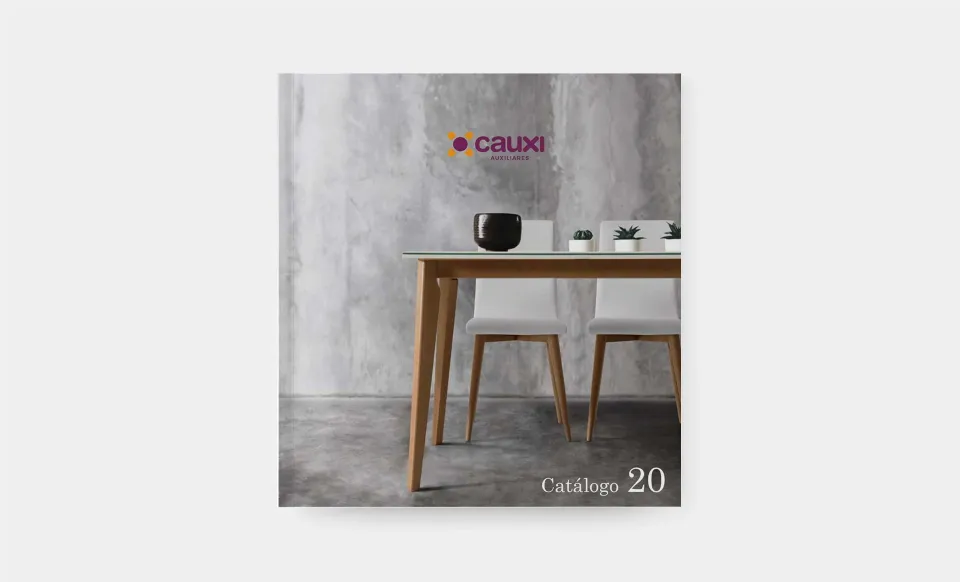 Portada del catálogo 2020 de Cauxi con una mesa de madera y sillas blancas