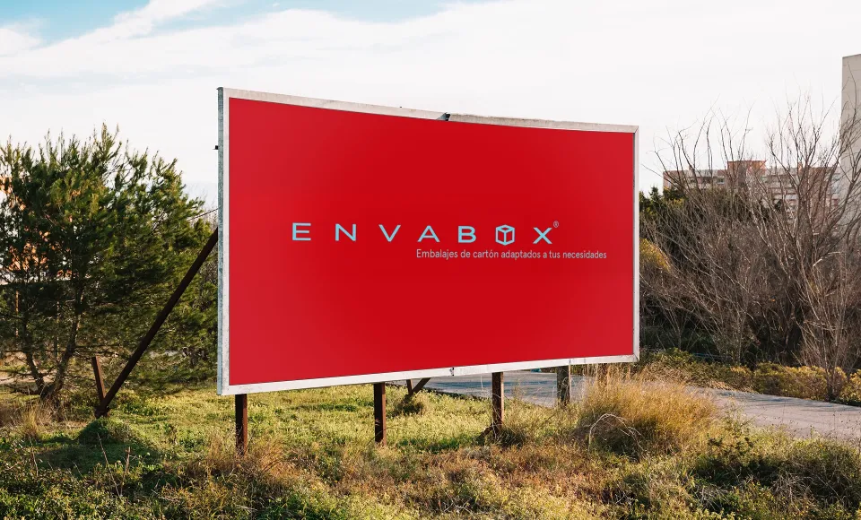 Valla publicitaria roja de Envabox instalada en un descampado junto a la carretera