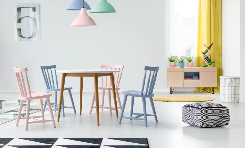 Dining area with a round wooden table and chairs in pastel pink and blue