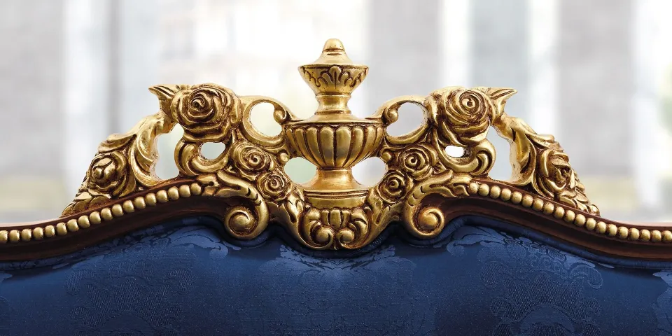 Close-up of the gilded carving on top of a navy-blue upholstered sofa