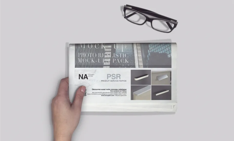 Hand holding a Navarro Azorín magazine mock-up next to a pair of glasses on a white background