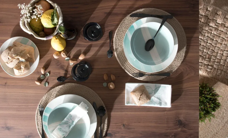 Mesa puesta con vajilla, salvamanteles de fibra y fruta sobre una mesa de madera