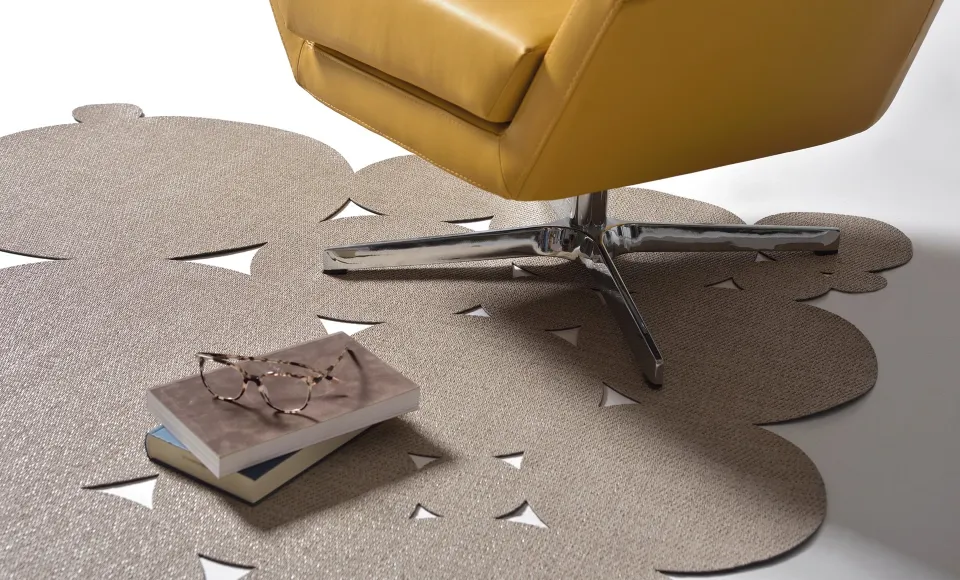 Alfombra troquelada de Parentesi Quadra junto a un sillón amarillo, con un libro y unas gafas