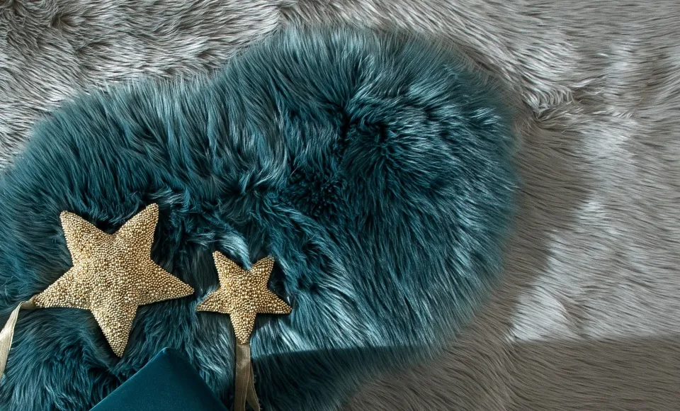 Cojín de pelo azul turquesa con estrellas doradas sobre una alfombra de pelo gris
