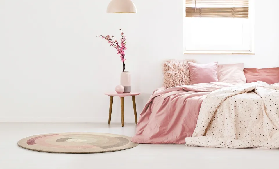 Dormitorio en tonos rosas con alfombra redonda y ropa de cama estampada