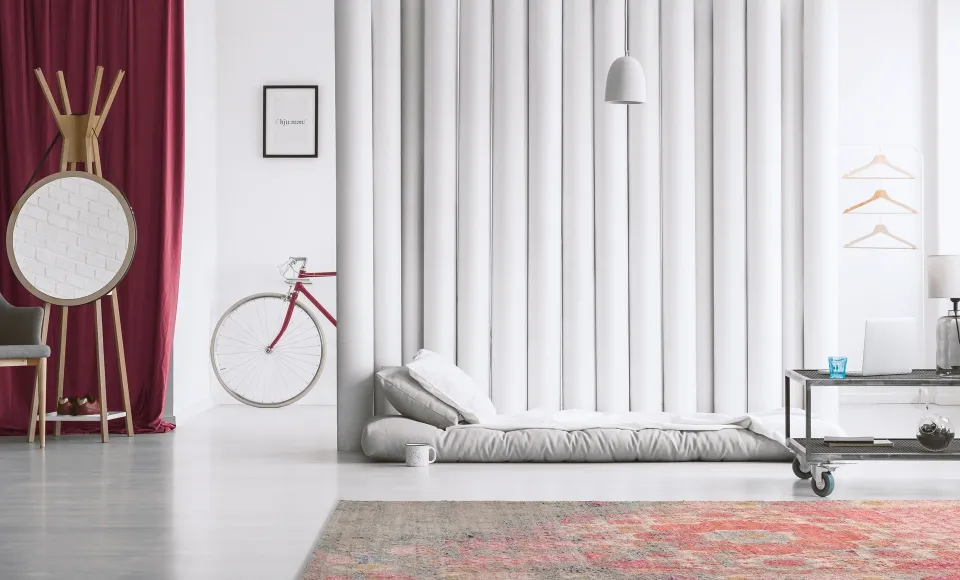 Alfombra estampada en rojo de Parentesi Quadra junto a un futón y una bicicleta