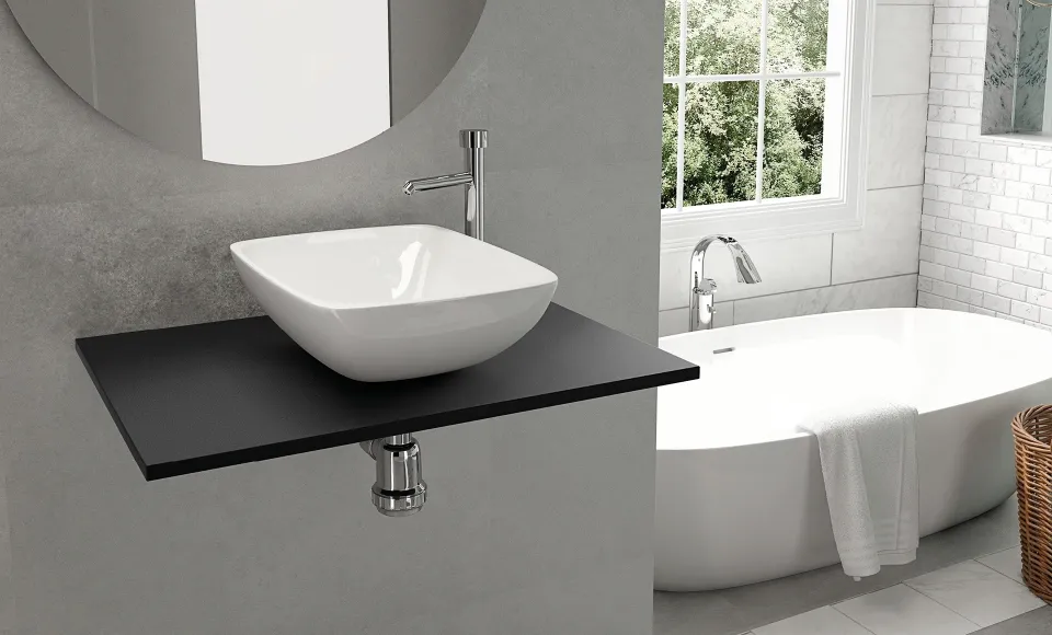 Lavabo blanco sobre encimera negra junto a una bañera exenta, en un baño con ventana a un jardín
