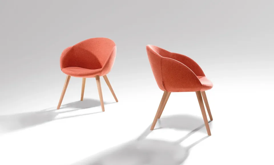 Two coral-coloured upholstered armchairs on wooden legs, photographed from different angles