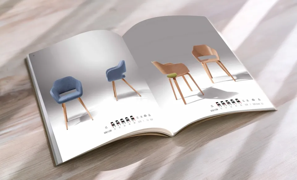 Catálogo abierto sobre una mesa de madera, con páginas de sillas tapizadas en azul y de madera