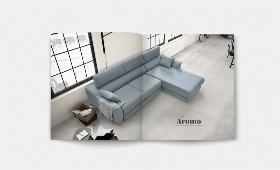 Página del catálogo con el sofá chaise longue «Aromo» en azul claro, en un salón tipo loft